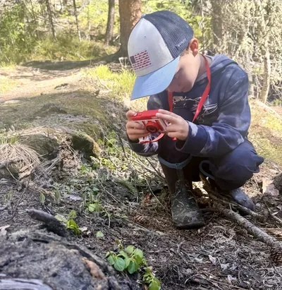 One of Jordan's sons crouching in the woods with his own camera